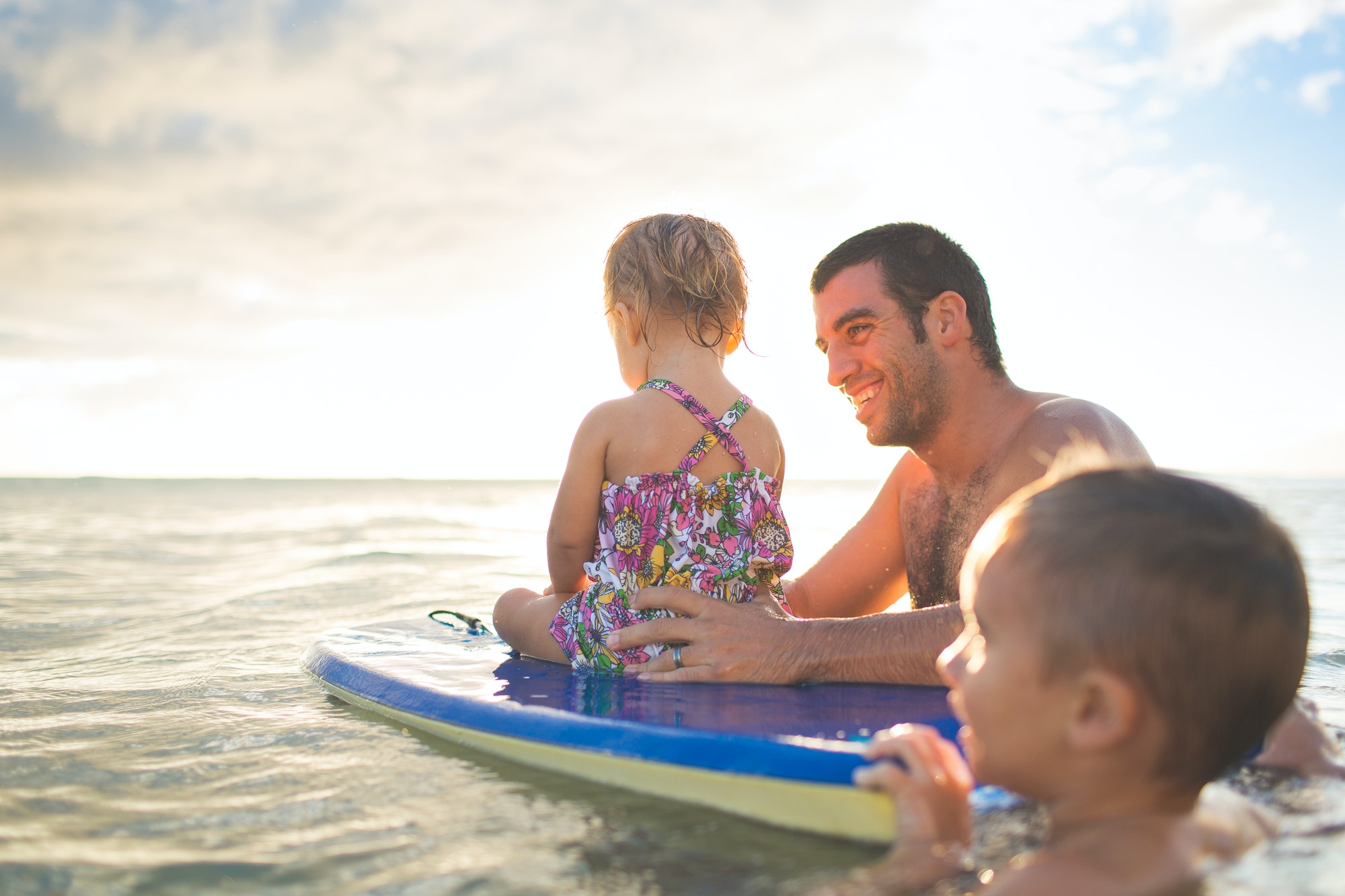 Dad and kids on boogie board in the ocean